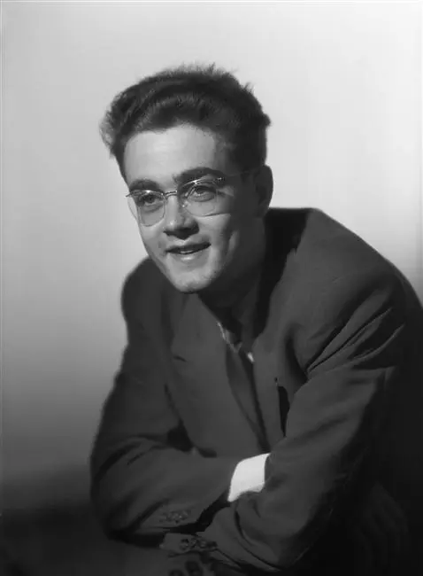 Portrait en noir et blanc de Michel Legrand à vingt ans, lunettes fines, sourire