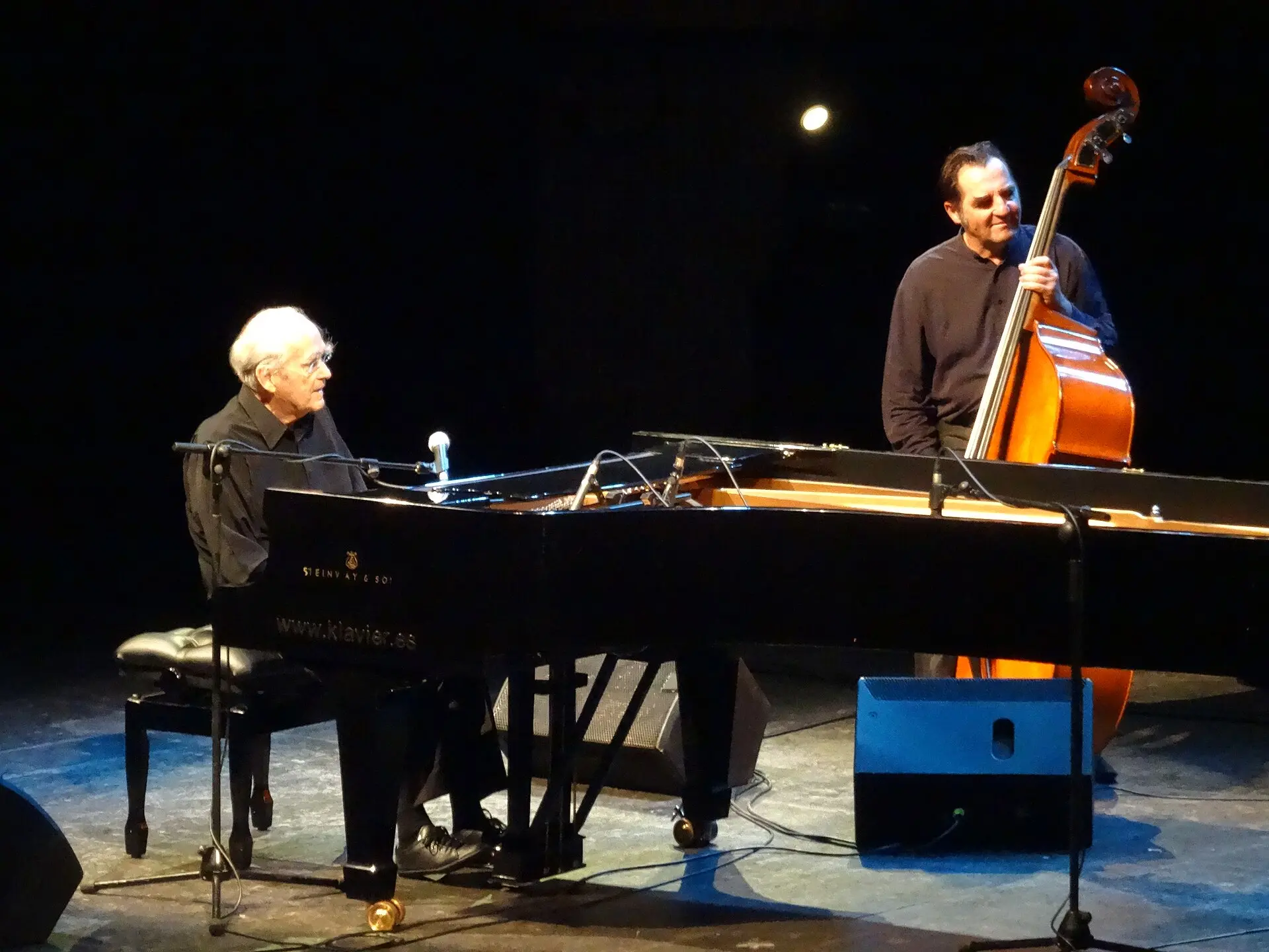 Michel Legrand au piano avec un contrebassiste, en trio jazz sur scène